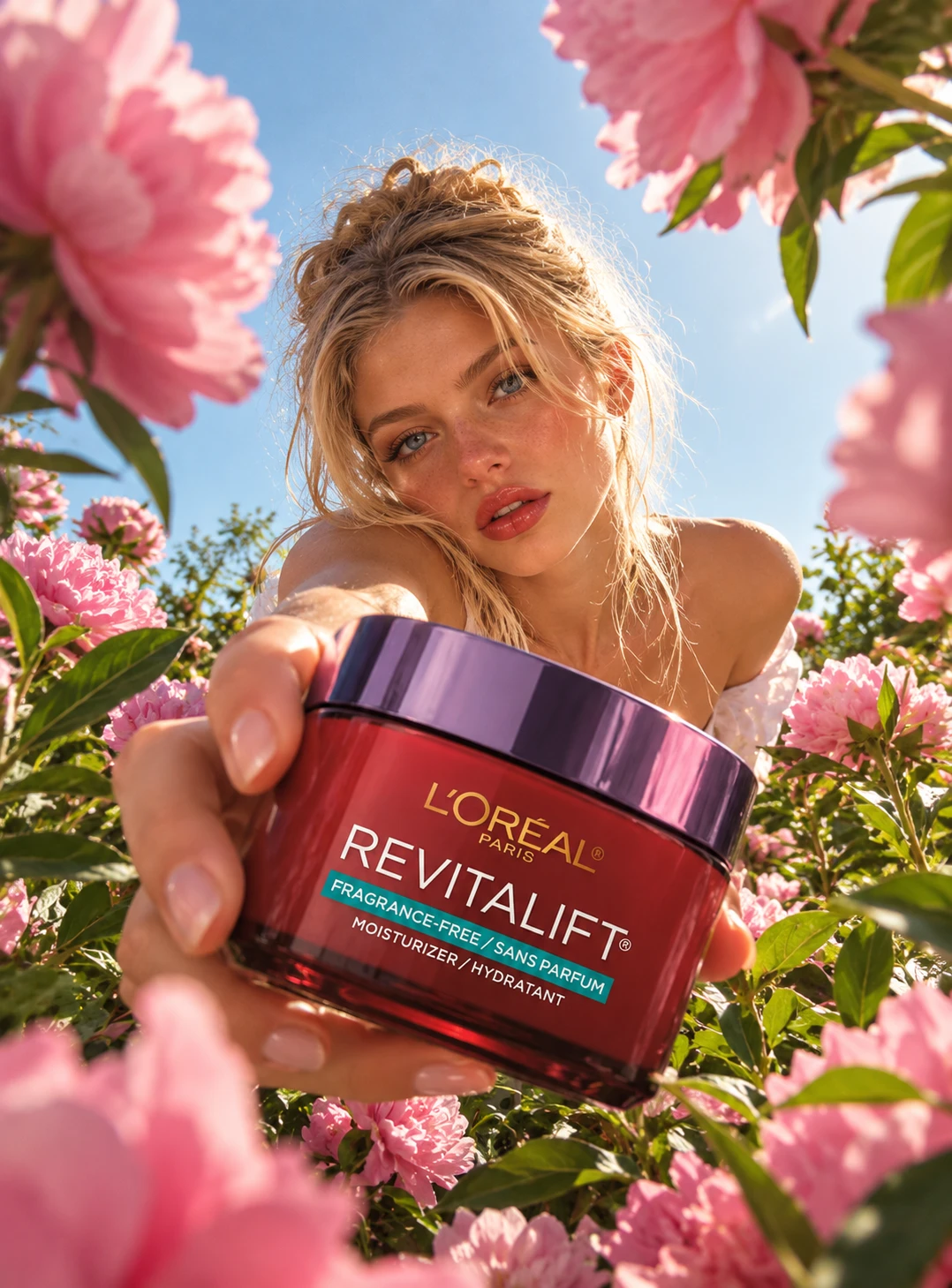 L'Oréal Revitalift poster: a model holds the red moisturiser jar toward the camera through a field of pink peonies